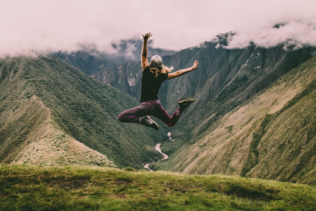 a woman jumping infront of mountains